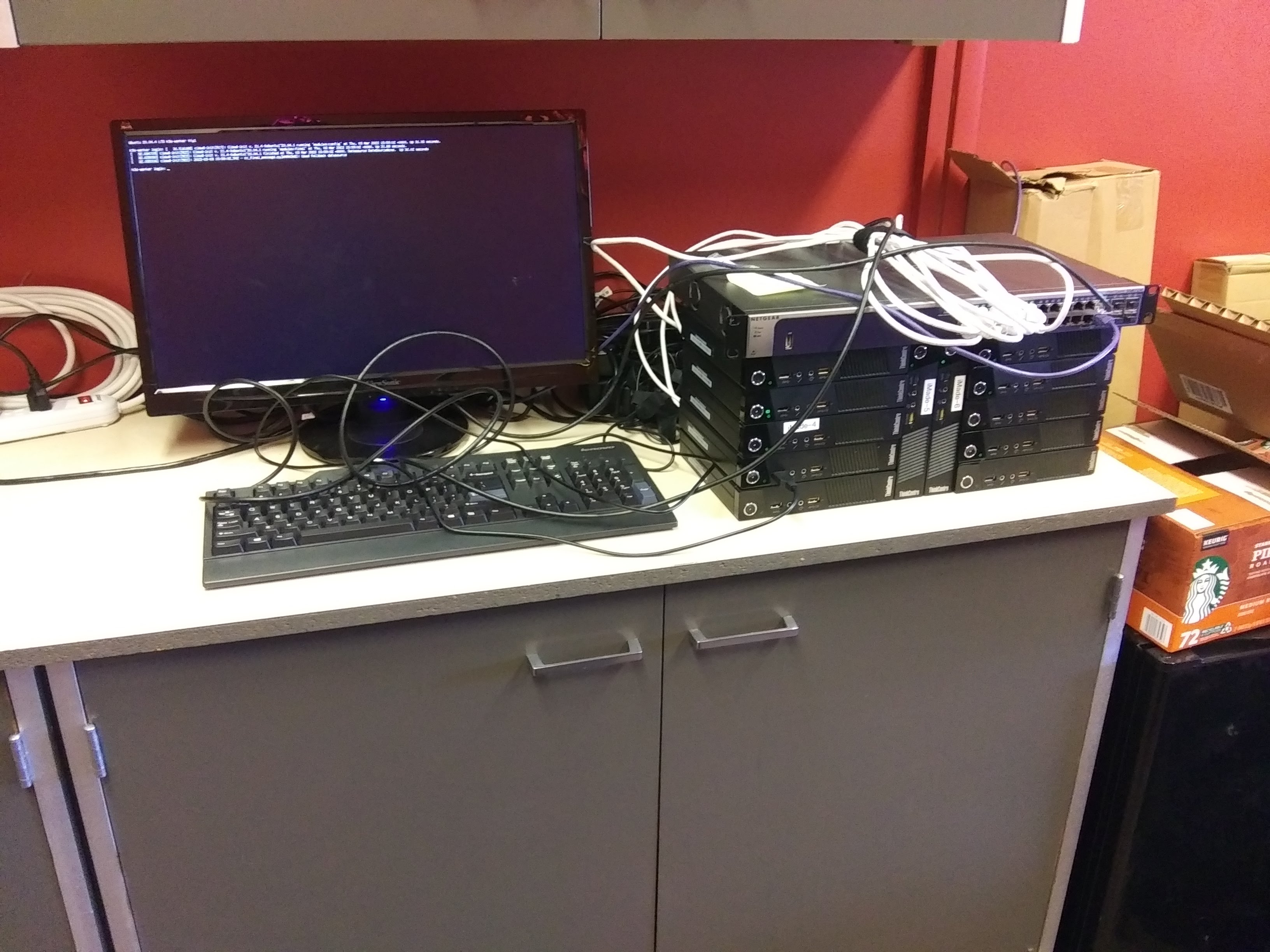 The initial NCS cluster — twelve Lenovo ThinkCentres on a lab bench with a switch